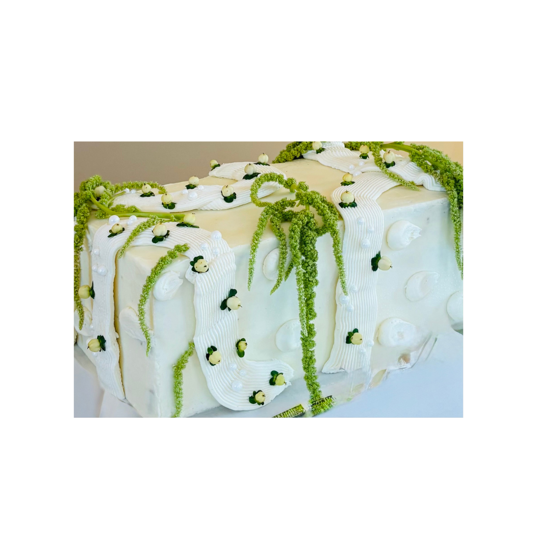 Elegant white celebration cake decorated with green botanicals and pearl accents